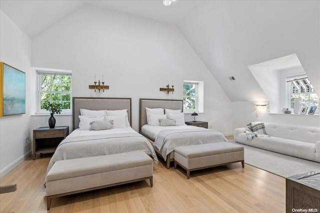 bedroom featuring multiple windows, high vaulted ceiling, and light hardwood / wood-style floors