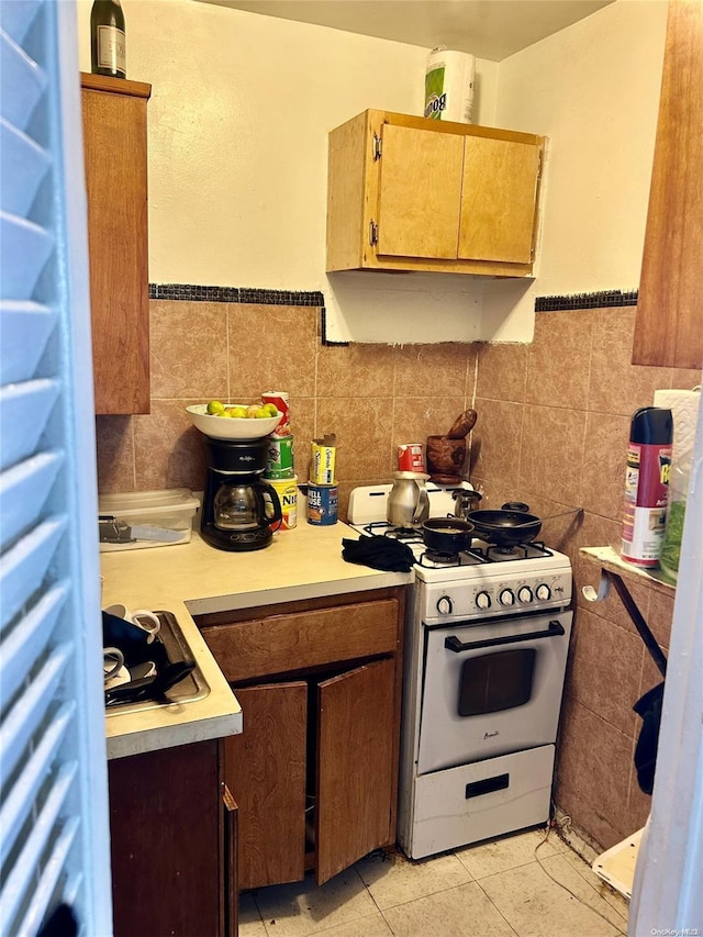 kitchen with light tile patterned floors, tile walls, and white gas stove