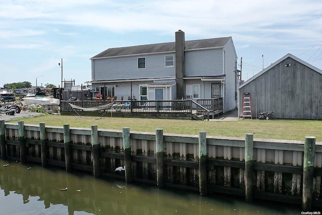 back of property featuring a deck with water view and a yard