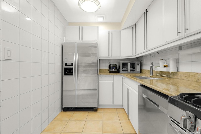 kitchen with light stone countertops, sink, light tile patterned flooring, white cabinets, and appliances with stainless steel finishes