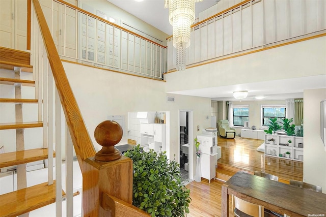 stairs with hardwood / wood-style flooring, a towering ceiling, and a chandelier