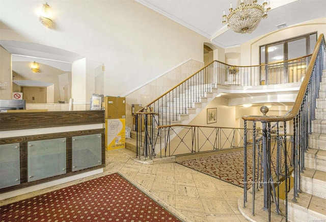 staircase with a chandelier, a high ceiling, and crown molding