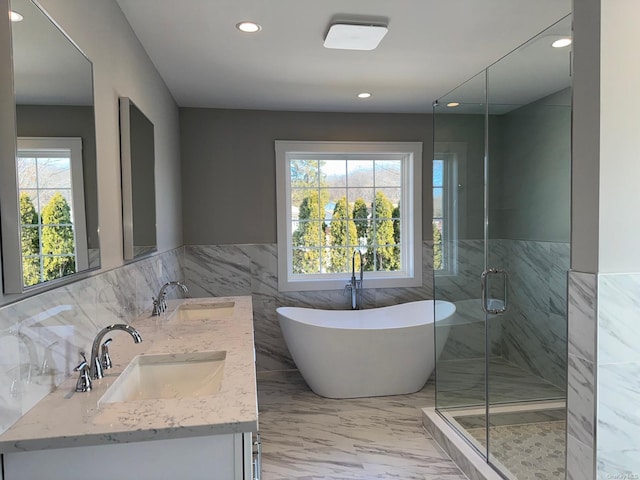 bathroom with vanity, shower with separate bathtub, a wealth of natural light, and tile walls