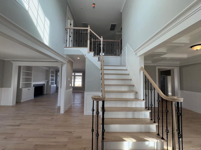 staircase featuring hardwood / wood-style floors, beam ceiling, built in shelves, and coffered ceiling