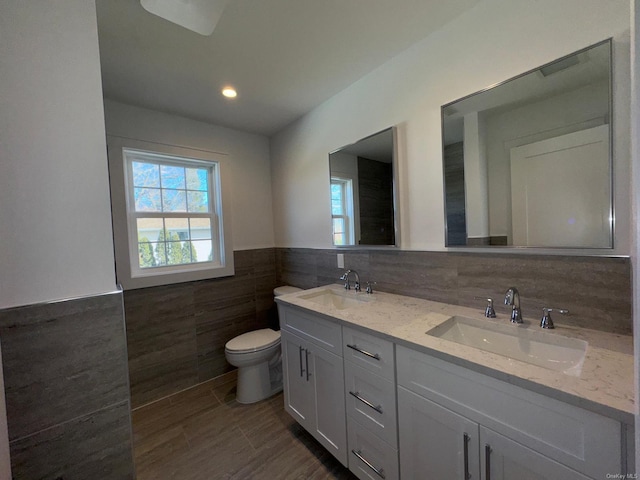 bathroom with vanity, toilet, and tile walls