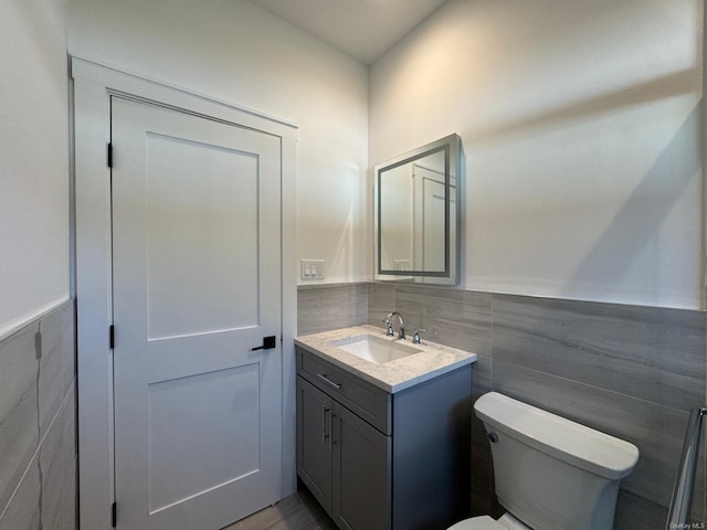 bathroom with vanity, tile walls, and toilet