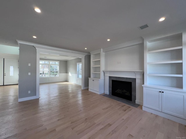 unfurnished living room featuring light hardwood / wood-style floors, built in features, and ornamental molding