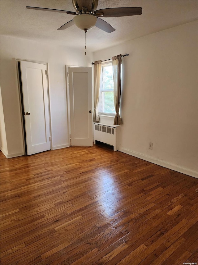 spare room featuring radiator, ceiling fan, and hardwood / wood-style floors