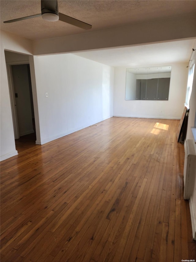 spare room featuring a textured ceiling, ceiling fan, and dark wood-type flooring