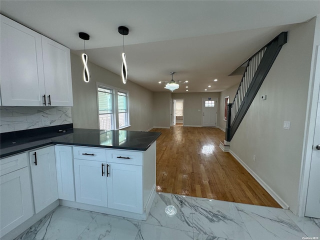 kitchen featuring white cabinetry, an inviting chandelier, light hardwood / wood-style floors, decorative light fixtures, and decorative backsplash