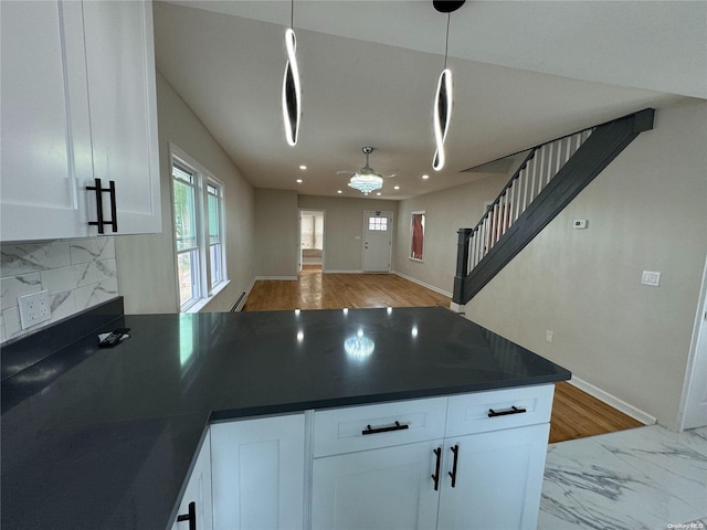 kitchen with backsplash, light hardwood / wood-style flooring, white cabinets, and hanging light fixtures