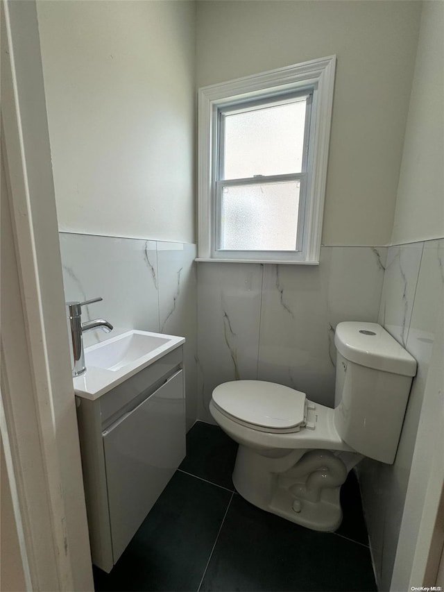 bathroom featuring tile patterned floors, vanity, toilet, and tile walls