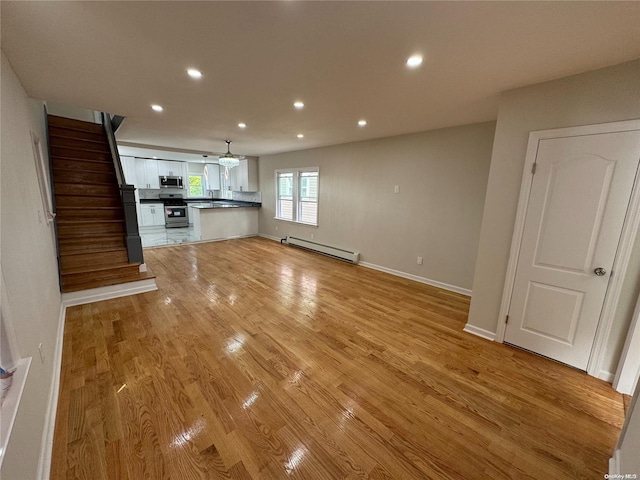 unfurnished living room with light hardwood / wood-style floors and a baseboard heating unit