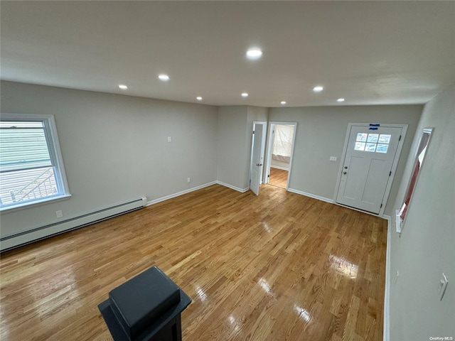 foyer entrance with a wealth of natural light, a baseboard radiator, and light wood-type flooring