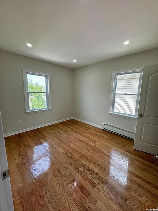 empty room with light hardwood / wood-style floors and baseboard heating