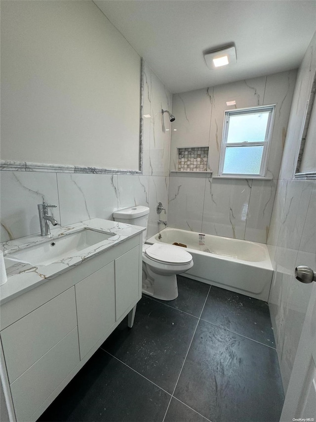 full bathroom with vanity, tile patterned floors, tiled shower / bath, toilet, and tile walls