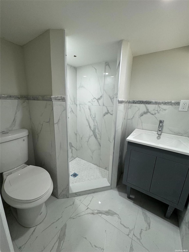 bathroom featuring vanity, a shower, toilet, and tile walls