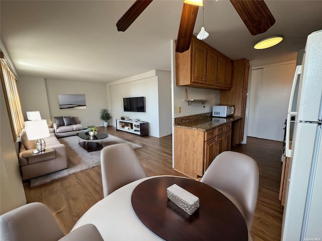 kitchen with dark hardwood / wood-style floors, dark stone counters, and white fridge