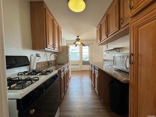 kitchen with hardwood / wood-style flooring, light stone counters, white appliances, and sink