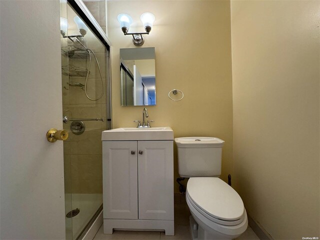 bathroom featuring tile patterned floors, vanity, a shower with shower door, and toilet