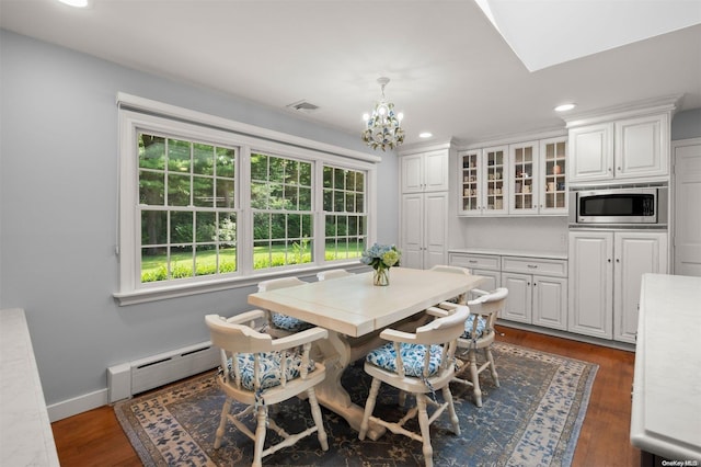 dining space featuring dark hardwood / wood-style floors, an inviting chandelier, and a baseboard heating unit