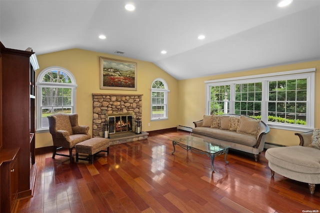 living room with a baseboard heating unit, dark hardwood / wood-style flooring, vaulted ceiling, and a stone fireplace