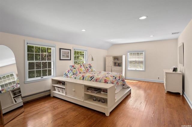 bedroom with hardwood / wood-style floors, lofted ceiling, and a baseboard heating unit