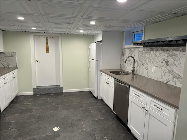 kitchen featuring dishwasher, sink, tasteful backsplash, white fridge, and white cabinetry