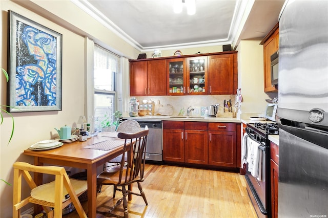 kitchen with sink, stainless steel appliances, crown molding, light hardwood / wood-style floors, and decorative backsplash