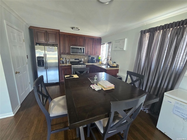 dining area featuring dark hardwood / wood-style flooring, ornamental molding, and sink