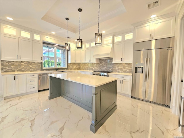 kitchen with a center island, white cabinetry, stainless steel appliances, and a tray ceiling