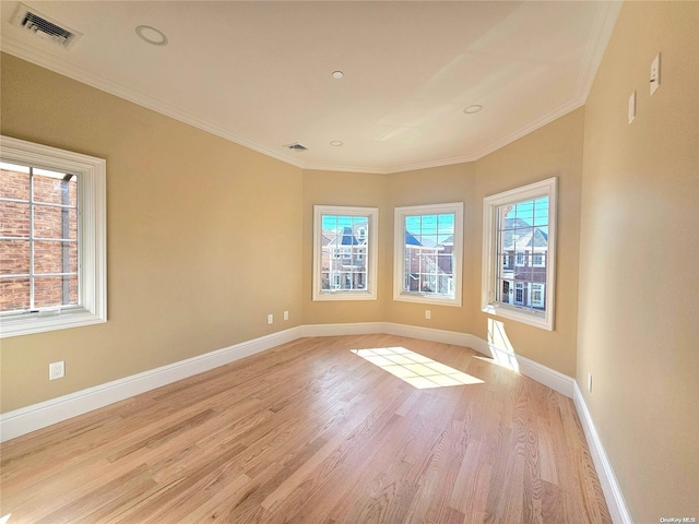 empty room featuring plenty of natural light, ornamental molding, and light hardwood / wood-style flooring