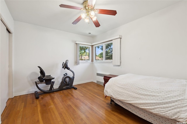 bedroom with a closet, radiator, ceiling fan, and hardwood / wood-style floors