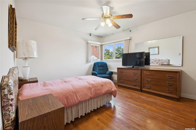 bedroom with wood-type flooring, ceiling fan, and radiator