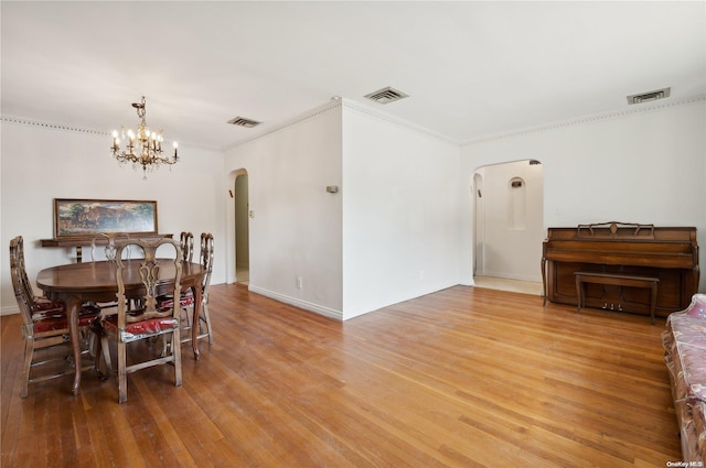 dining space with hardwood / wood-style flooring, an inviting chandelier, and ornamental molding