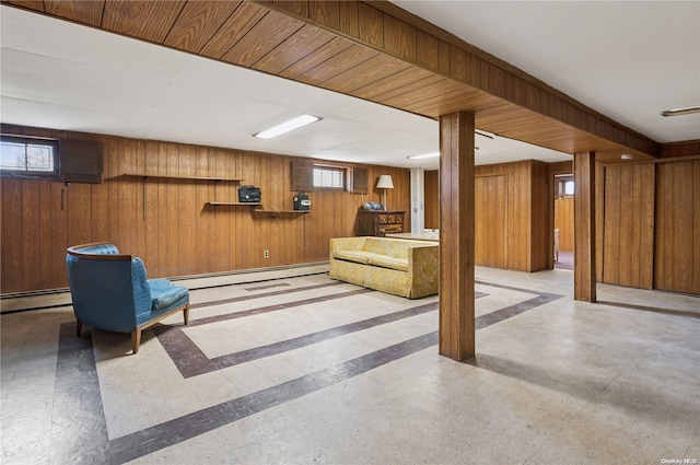 basement with plenty of natural light, wooden walls, and a baseboard radiator