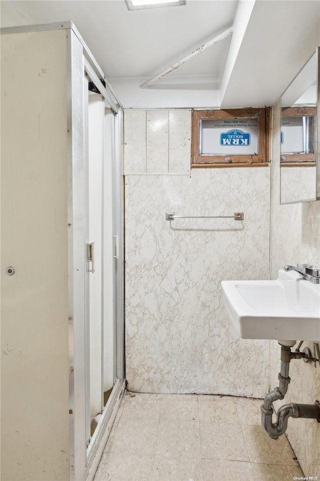 bathroom with tile walls, sink, and an enclosed shower