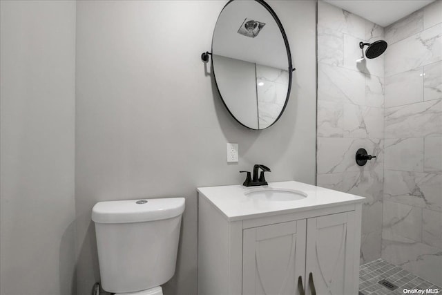 bathroom featuring vanity, toilet, and tiled shower