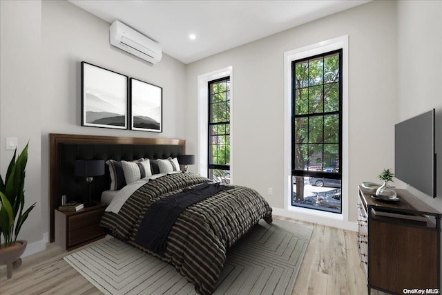 bedroom with an AC wall unit and light hardwood / wood-style floors