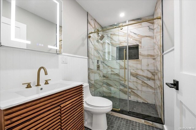 bathroom featuring tile patterned floors, vanity, toilet, and a shower with door