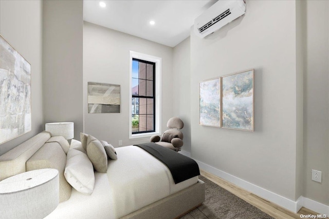 bedroom with hardwood / wood-style flooring and a wall unit AC