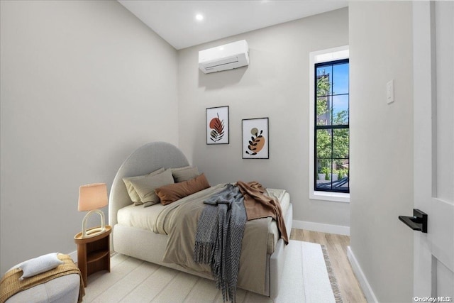 bedroom with light wood-type flooring and an AC wall unit