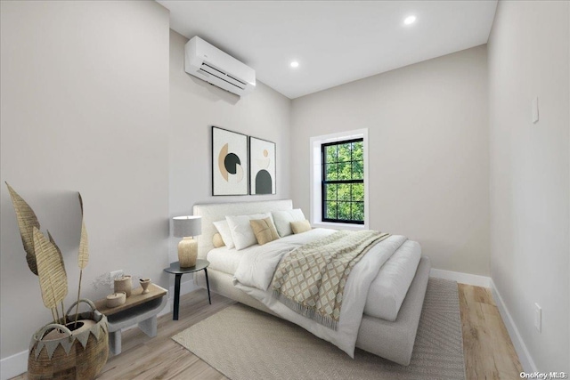 bedroom with an AC wall unit and light wood-type flooring