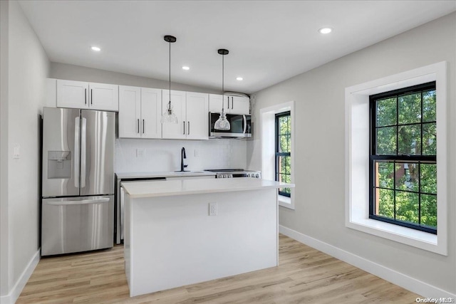 kitchen with appliances with stainless steel finishes, white cabinetry, and a healthy amount of sunlight