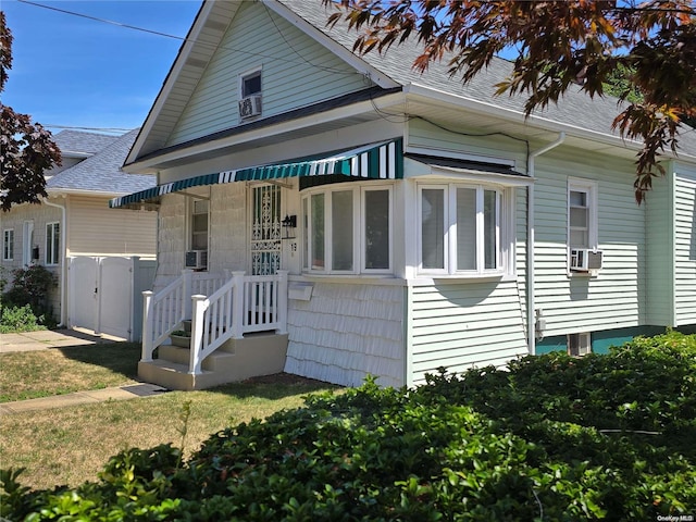 view of front of home with cooling unit and a front lawn