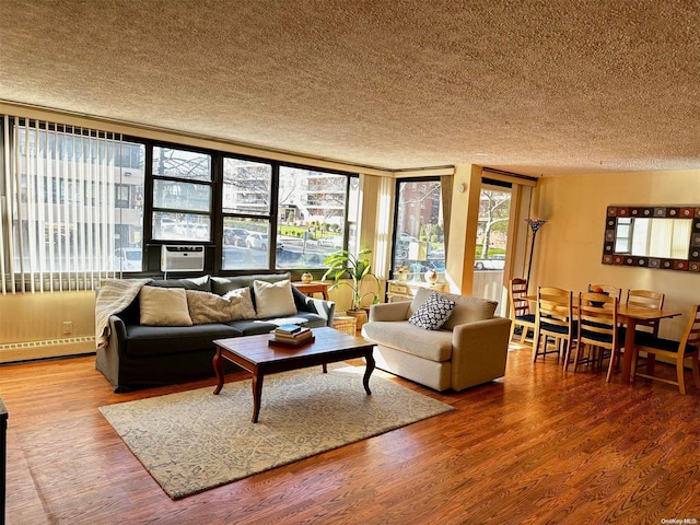 living room featuring hardwood / wood-style floors, cooling unit, a textured ceiling, and a baseboard heating unit