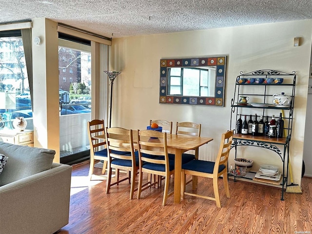 dining space featuring hardwood / wood-style flooring, a textured ceiling, and a wealth of natural light