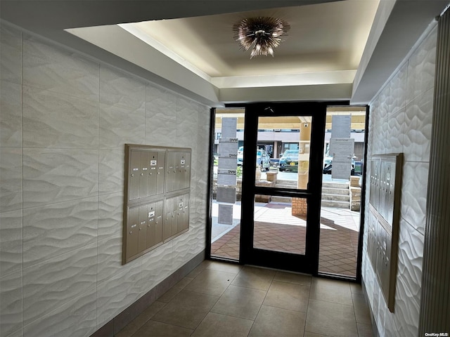 doorway to outside with tile patterned flooring, mail boxes, a raised ceiling, and tile walls