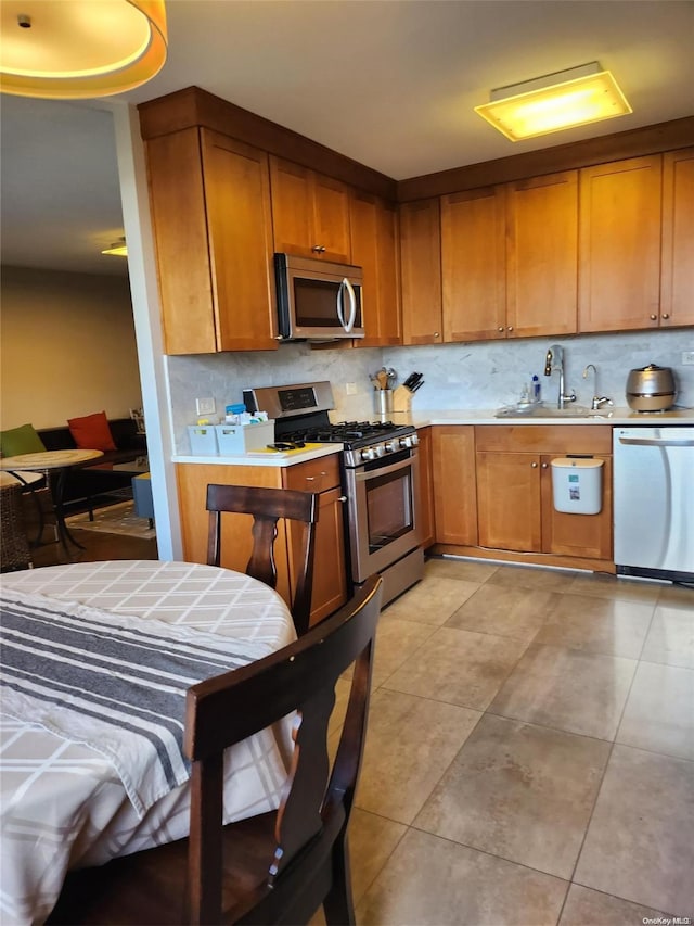 kitchen featuring appliances with stainless steel finishes, tasteful backsplash, light tile patterned floors, and sink