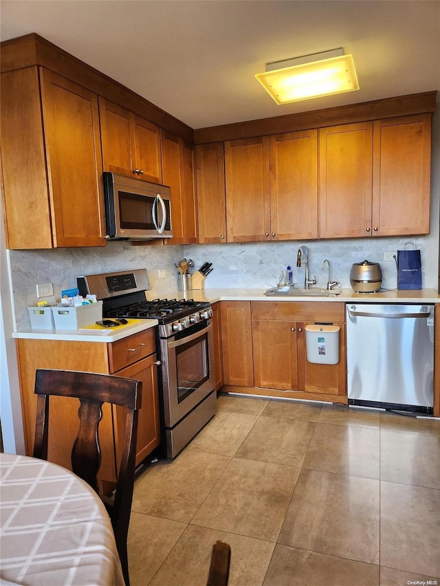 kitchen with decorative backsplash, light tile patterned flooring, sink, and appliances with stainless steel finishes